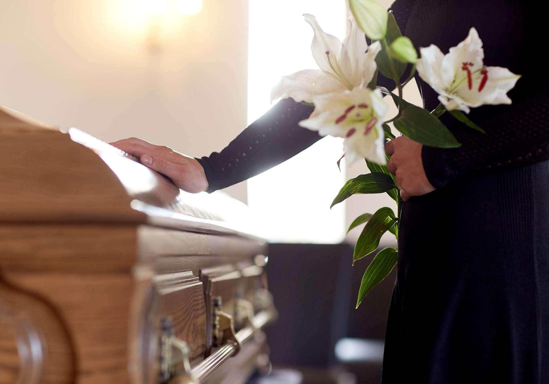 Woman holding a bunch of Lilies at a coffin